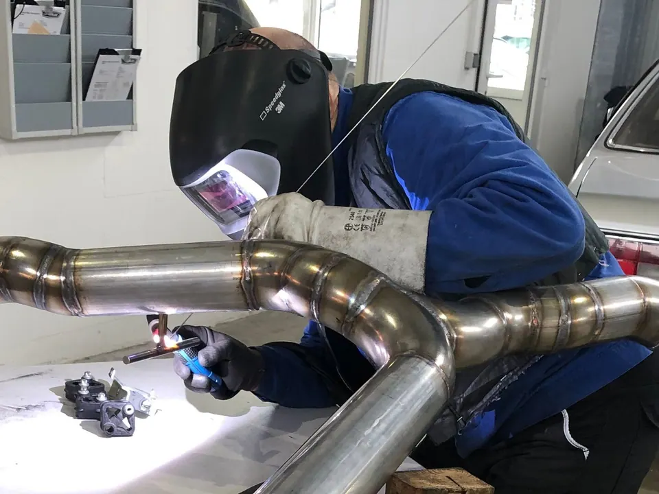 Techniker schweißt Auspuffanlage